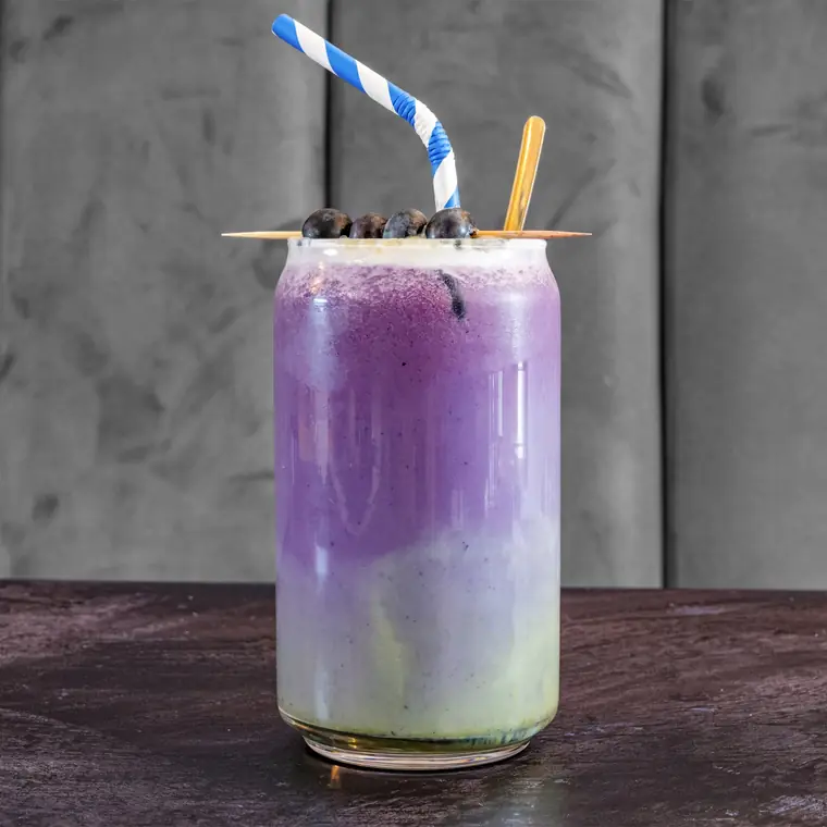 Layered blueberry smoothie topped with fresh blueberries.