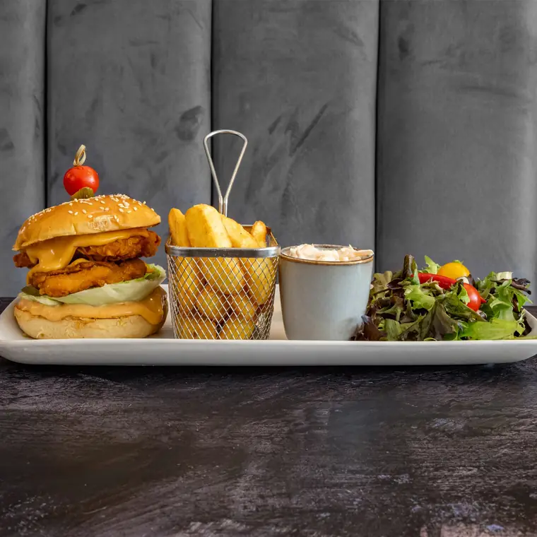 Fried chicken burger with fries, coleslaw and a side salad.