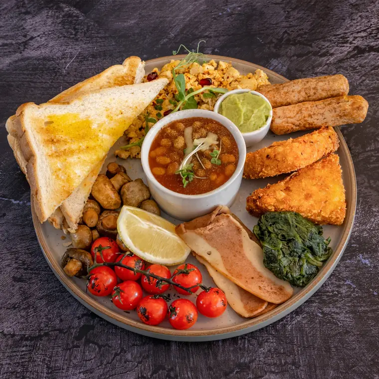 Vegan breakfast — scrambled tofu, vegan bacon, beans, tomatoes, spinach and toast.