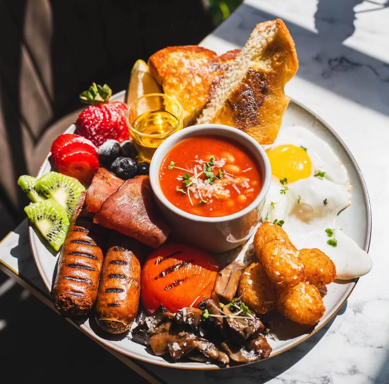 Halal full English on sunlit marble — chicken sausages, turkey rashers, fried egg, beans, hash browns, grilled tomato, mushrooms and toast