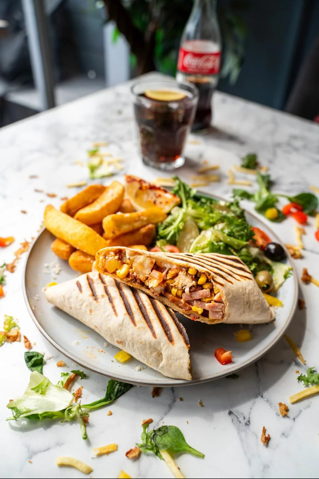 A grilled panini cut in half at TenTen — chicken, turkey ham, sweetcorn and melted cheese — served with chunky chips and a dressed salad on a marble table.